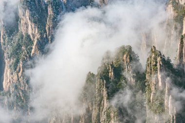 Huangshan Ulusal Parkı 'nın dağlık tepelerinde güneş doğarken bulutlar. Çin.