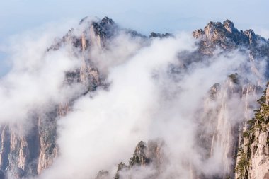 Huangshan Ulusal Parkı 'nın dağlık tepelerinde güneş doğarken bulutlar. Çin.