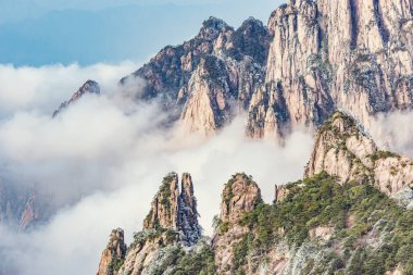 Huangshan Ulusal Parkı 'nın dağlık tepelerinde güneş doğarken bulutlar. Çin.