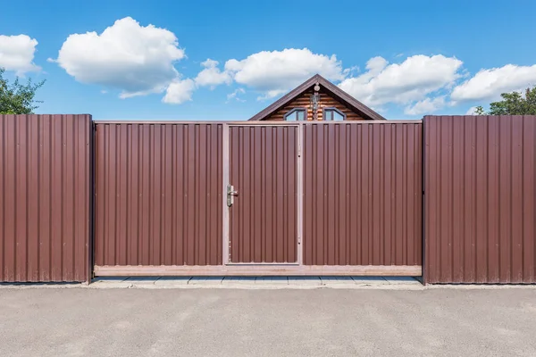 Metallic new gate by the house at summer time.