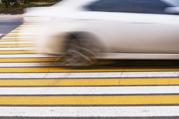 Автомобиль быстро движется по асфальтовому перекрестку.