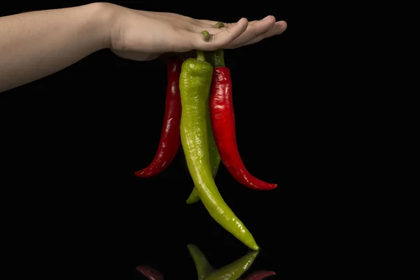 Mehrere Stücke roter Paprika männliche Hände schwarzer Hintergrund — Stockfoto