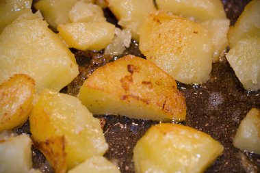 Altın kahverengi renkli bir tavada kızarmış patates. Eritilmiş tereyağı.