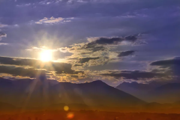 Sunrise in the mountains. A clear beautiful morning begins. Clouds after a thunderstorm with lightning and thunder over the tops of the ridges, with strong wind and rain