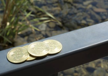 Birkaç bitcoinyyat güvertesinde korkuluk üzerinde sarılmak. Okyanus. Yaz. Kıyıya yakın taşlar. Finansal istikrar. Başarı. Metin için kopyalama alanı ile arka plan