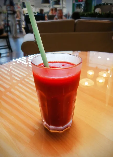 Ein Glas Erdbeer-Smoothie auf einem gelben Glastisch in einem Café — Stockfoto