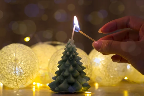 Frohe Weihnachten und ein gutes neues Jahr, Grußkarte. schöne Dekoration für die Feiertage. Hand eines Mädchens, das eine Kerze anzündet. dekorativer roter Hintergrund und goldener Bokeh-Kranz. Weihnachtsdekoration — Stockfoto