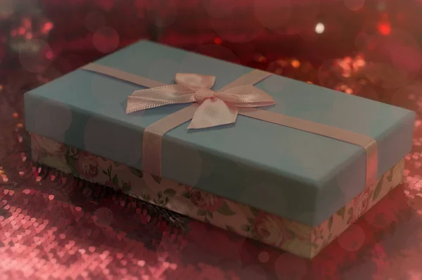 Scatole regalo si trovano su un tessuto rosso lucido. Pacchetto di regali per Christmas.bokeh, piccolo albero, sfondo festivo luminoso. Sfocatura. Regali di Natale.Regalo di Natale.Shopping natalizio . — Foto Stock