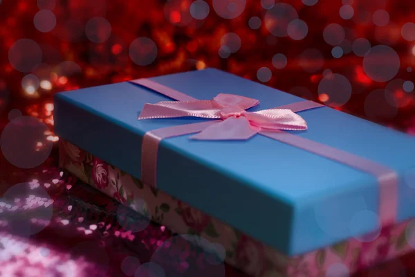 Cadeaudoosjes liggen op een rood glanzende stof. Pakket van geschenken voor Christmas.bokeh, kleine boom, heldere feestelijke achtergrond. Vervagend. Kerstcadeau.Kerstcadeau.Kerstinkopen. — Stockfoto