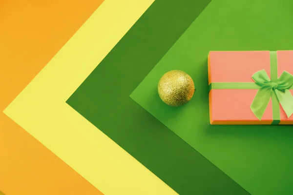 Christmas. Gifts. Design. Christmas concept. New Year concept. Christmas mock up. Minimalism. Improvisation. Space for text. On a multicolor background lies a pink gift box tied with a ribbon. Nearby