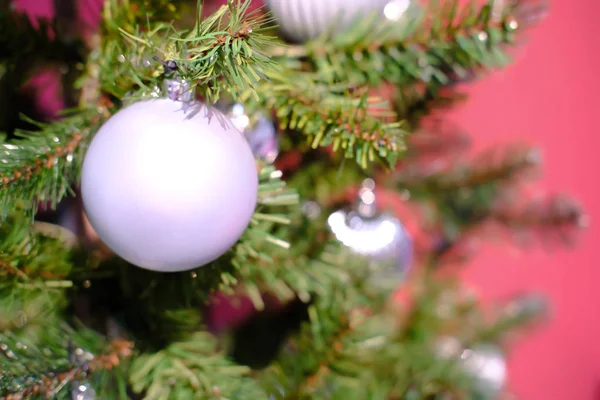 Decorações de Natal, ornamentos, decorações de Natal, bugigangas, topper árvore de Natal, pendurar em uma árvore de Natal artificial em um fundo vermelho iluminado da frente — Fotografia de Stock