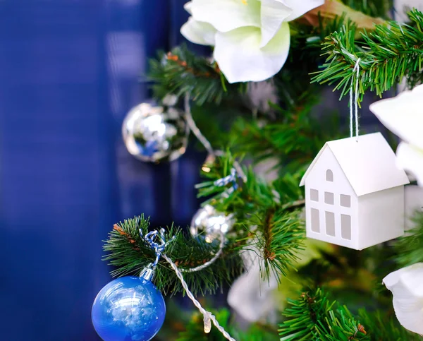 Konzept: Eigenes Wohnen im nächsten Jahr. Kredit. Hypothek. Darlehen. Weihnachtsdekoration eines Weihnachtsbaums. ein Spielzeughaus hing an einem Weihnachtsbaum. — Stockfoto