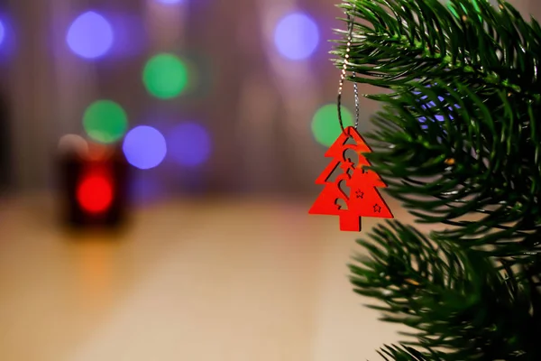 Ein hölzernes weihnachtsspielzeug hängt an einem üppigen fichtenzweig, der hintergrund verschwimmt im kerzenlicht. Bokeh Raum für Text. — Stockfoto