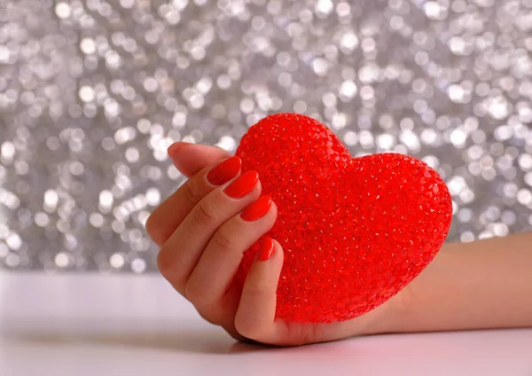 World Heart Day Concept: Female hand holding a red heart on blurred background