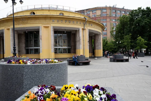 Moskova, Rusya, 25 Mayıs 2019: Novokuznetsk metro istasyonunun yuvarlak sarı binası, parlak renkli bahar çiçekleri ile ön planda çiçek tarhları