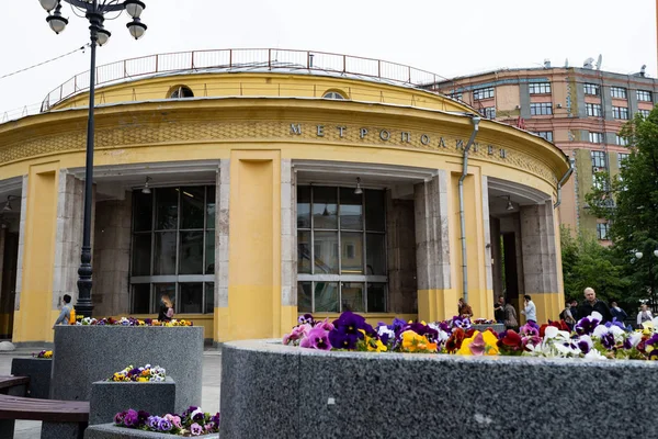 Moskva, Ryssland, maj 25, 2019: Rund gul byggnad av Novokuznetsk tunnelbanestation i förgrunden blomrabatter med ljusa färgglada vårblommor — Stockfoto