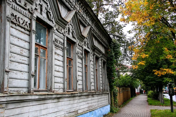 Herfst stadsgezicht in een klein Russisch stadje, een oud houten huis op een achtergrond van herfst bladeren. — Stockfoto