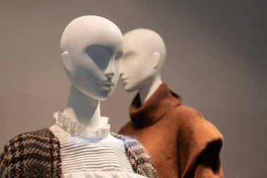 Sonbahar ve kış için bir mağaza vitrininde kalın kıyafetler giymiş iki manken. Mevsimlik satış.