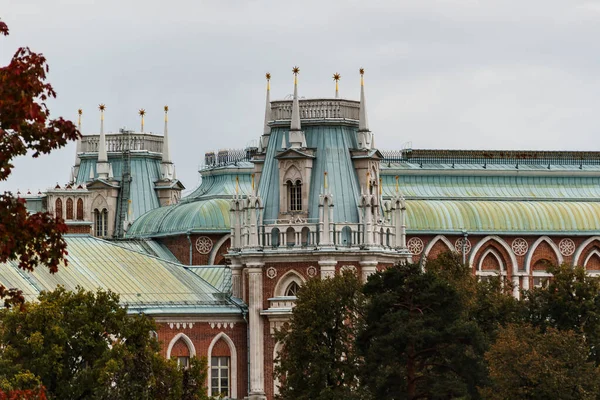 The tower of a beautiful old castle surrounded by autumn trees against a gray sky. — Stock Photo, Image