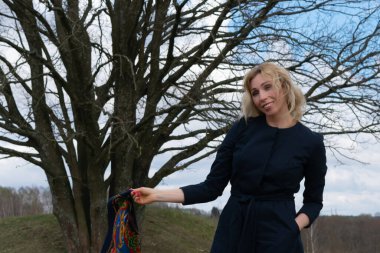 Uzun saçlı bir sarışın özgürlüğün tadını çıkarıyor. Orta yaşlı bir kadın yeşil tarlaların arasında toprak bir yolda tek başına yürüyor.