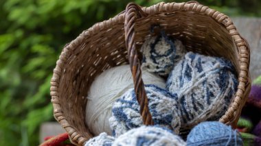 Hasır sepetin içinde mavi ve beyaz yün toplar, çok renkli örgü battaniyenin üzerinde. Doğal arka plan. Kopya uzayı olan yatay poster. Örgü örmek için iplik.