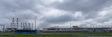 Moskova 'daki endüstriyel şehir manzarası, modern bir tren otoyolun yakınına, fabrika borularının arka planına ve bulutlu gri gökyüzüne doğru ilerliyor.