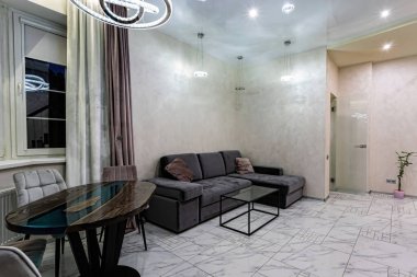 Geniş ve rahat bir oturma odası, kanepe ve pencere kenarında bir masa..