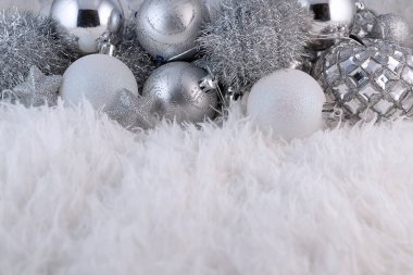 Gümüş Noel topları olan bir poster. Kabarık beyaz kürk arka planında fotokopi alanı olan güzel bir Noel kompozisyonu.