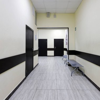 Modern ofis binasının boş koridoru. Bej duvarlı çok uzun bir koridor boyunca bir sürü kahverengi kapı var..