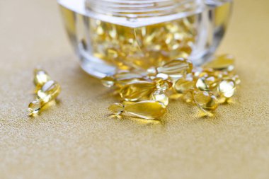 Omega 3 'lü balık yağı kapsülleri ve sarı arka planda D vitamini. Sağlıklı vitaminler. Metnin için bir kopya alanı. Minimalist soyut tıp kavramı.