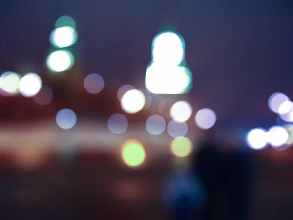 Defocused photography. Lights and bokeh on the street at christmas. Abstract dark blurry urban background.