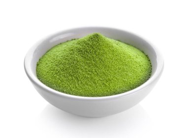 Beyaz arka planda bir kasede yeşil çay tozu