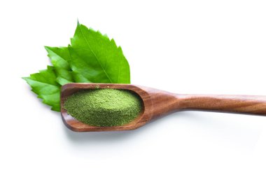 Beyaz arka planda kaşıkta yeşil çay tozu
