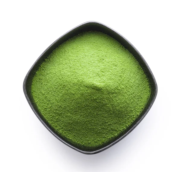Beyaz arka planda bir kasede yeşil çay tozu