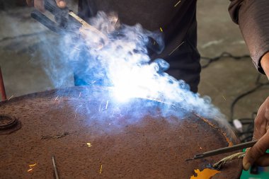 Kaynak teli, Mor duman ve ışık ile elektrik kaynakçı çelik kesme eski petrol tankı