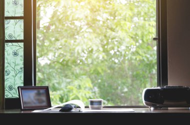 Sabah güneşi ile pencerenin dışında doğal bir atmosfere sahip bir çalışma masası.