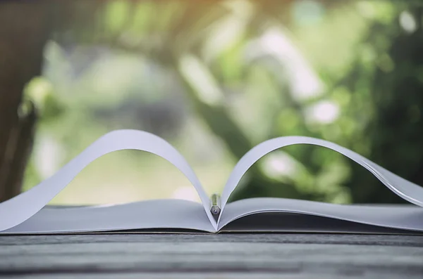 Kitap beyaz nota ve sarı kalem Ahşap zemin eski, yeşil yaprakların arka planda beyaz
