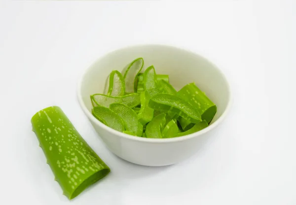 Beyaz arka plan üzerinde izole beyaz bir fincan taze aloe vera dilimleri yakın.