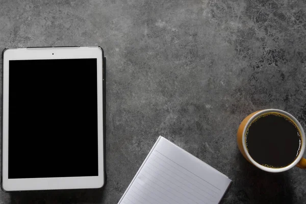 Coffee break. Top view yellow cup of coffee with tablet and Note paper on a table background