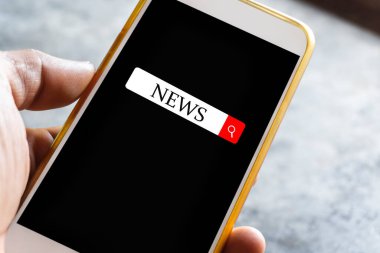 Bir adamın eli ekranda siyah ekranlı bir akıllı telefondan haber arıyor. Haberler için bir kutu var. Özellikle Coronavirus veya Covid-19 durumunda sosyal medyayı kullanarak.
