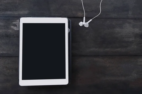 Tahta masa yüksekliğinde dijital tablet ve kulaklıklar kopyalama alanı ile