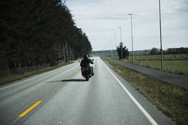 Siyah deri ceket ve kask lı bisikletçinin arka görünümü