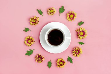 Beyaz fincanda Americano kahvesi ve pembe kasımpatı çiçekleri, yeşil yapraklı yeşil nane arkaplanı. 