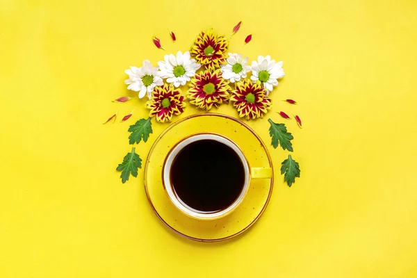 white cup with Americano coffee and round floral frame of pink chrysanthemum flowers, green leaves on green mint background