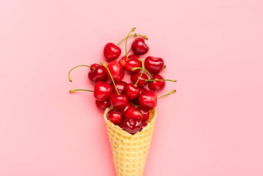 Vişneli waffle külahında taze dondurma. Pembe arka planda taze vişneli dondurma. Üst Manzara. Uzayı kopyala Yaz yaratıcı konsepti Düz Sağlıklı yiyecekler