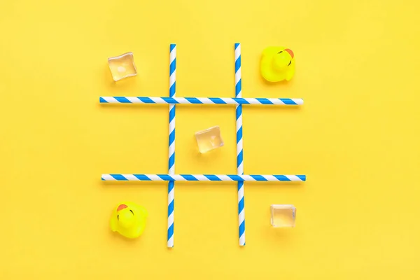 Juguete de pato, cubitos de hielo, tubos de papel con rayas azules para bebidas sobre un fondo amarillo. Batalla en el mar, tic tac toe concepto de juego Composición creativa Flat lay Vista superior —  Fotos de Stock