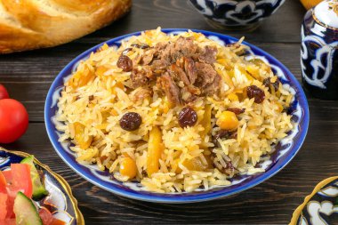 Ulusal Özbek pilavı et, domates salatası, salatalık, geleneksel desenli soğan, kişniş, kiraz domates, sarımsaklı tortilla - koyu ahşap masa üzerine yapıştırılır