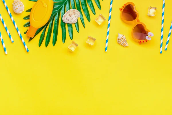 Swimming accessories - sunblock, heart - shaped glasses, ice cube, palm, shells, drinking paper straws for party with blue stripes isolated on yellow background Flat lay Top view Summer concept.