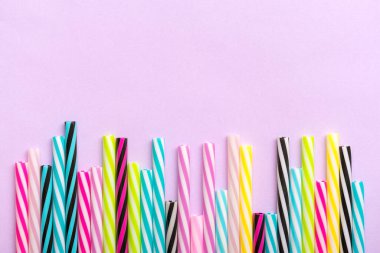 Eflatun arka planda parti için şeritli pipet içmek. Yaz kokteylleri için renkli plastik tüplerin en üst görüntüsü. Boşluğu kopyala Doğum günü, parti, yaratıcı, sanat konsepti.