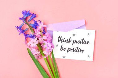 Bir buket sümbül çiçek, leylak zarf ve pembe arka plan üzerine beyaz not kağıdı. Üst manzara çiçekli bayram kartı. Metin:.